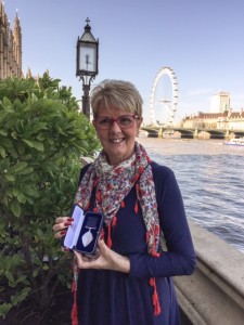 Monica holding her BCA medal in London.